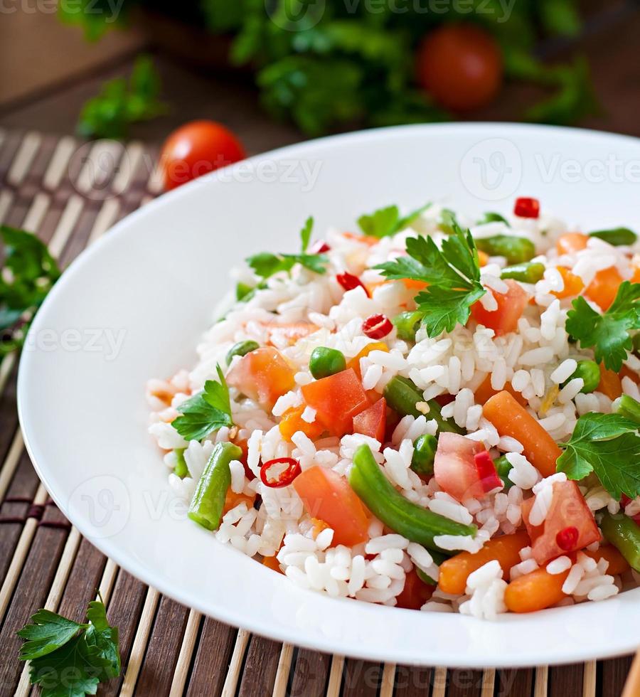 apetitoso arroz saludable con verduras en un plato blanco sobre un fondo de madera. foto