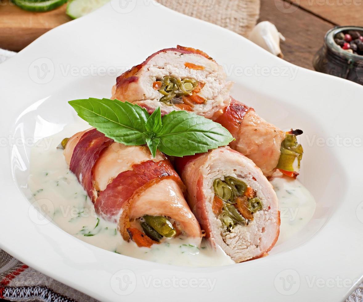 Delicious chicken rolls stuffed with green beans and carrots wrapped in strips of bacon photo