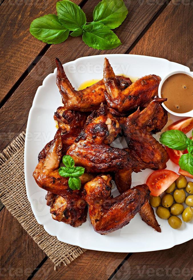 Plate of chicken wings on wooden background photo