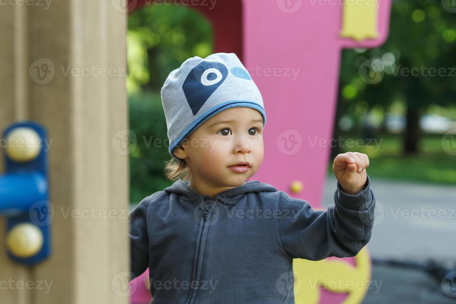 Cute little boy playing on a playground in a city park photo