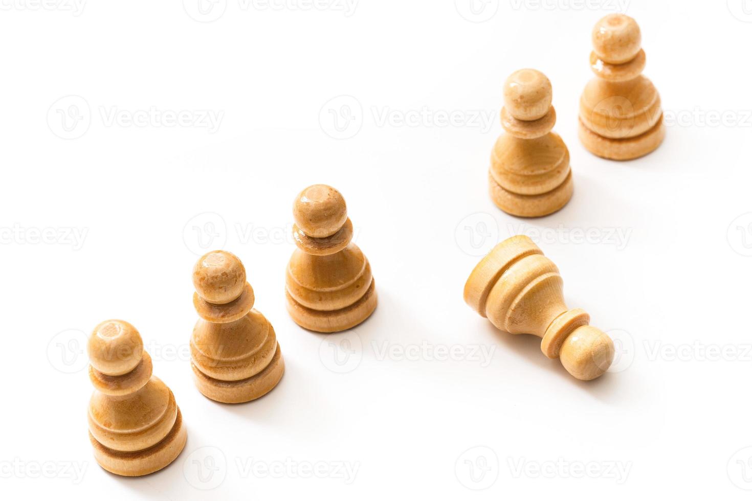 Wooden chessmen standing with one chess pawn lying. photo