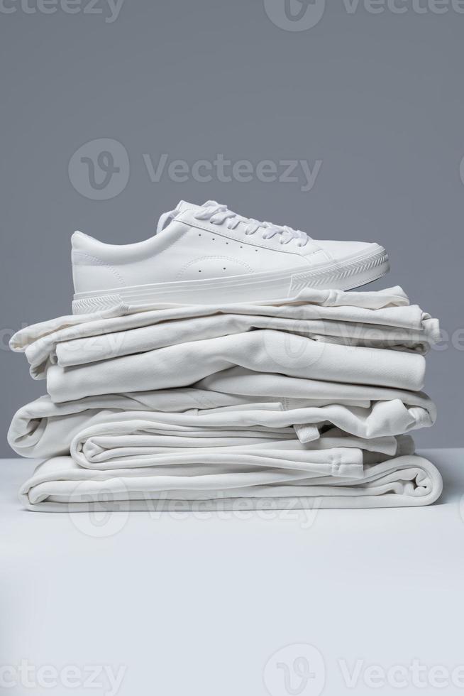 Stack of white clothes and stylish trainers photo