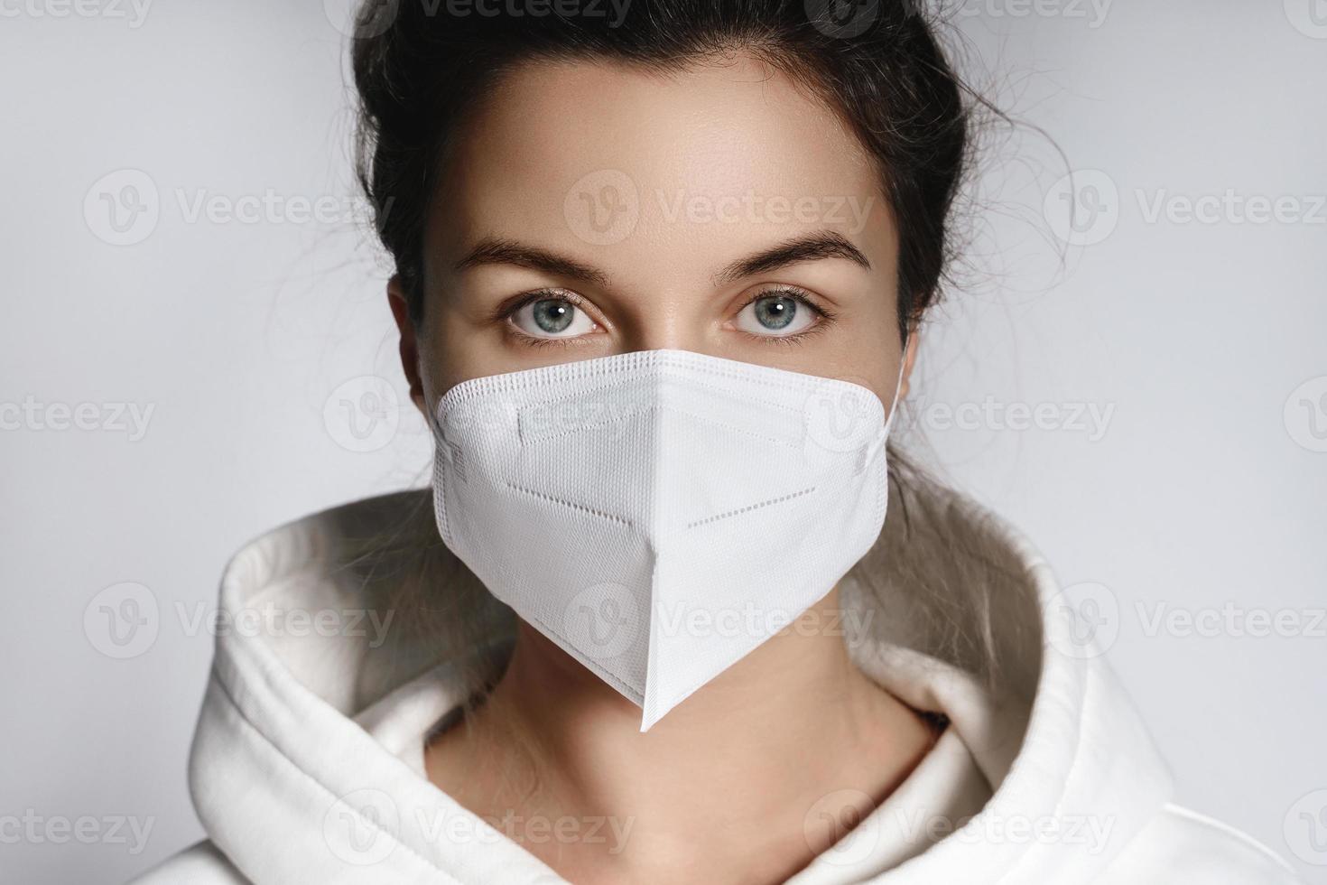 Young woman wearing white hoodie and ffp2 respirator mask photo