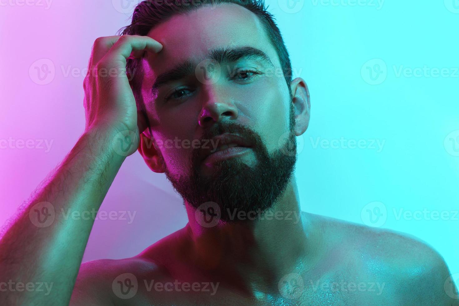 Handsome young man with wet skin in neon light photo