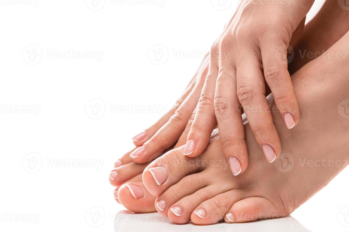 Female feet and hands with soft skin, french manicure and pedicure on white background photo