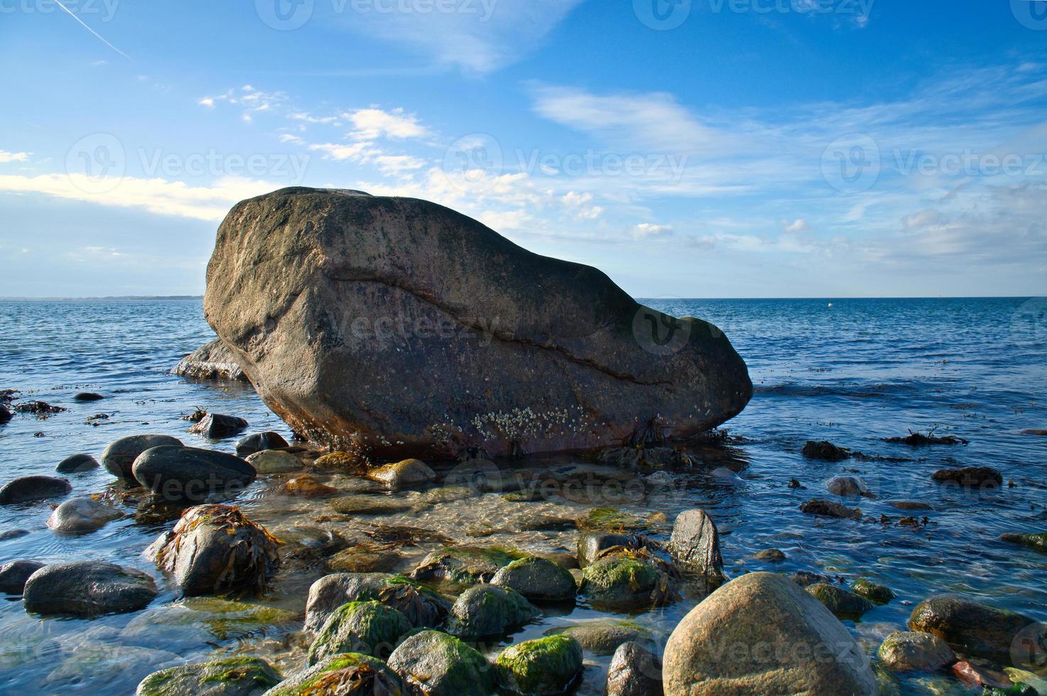 Large stone in the water on the beach in the sea. Danish coast on a sunny day photo
