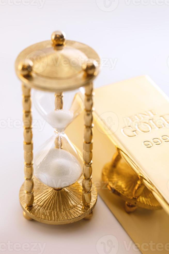 Hourglass and fine gold bullion. Concept of investment. photo