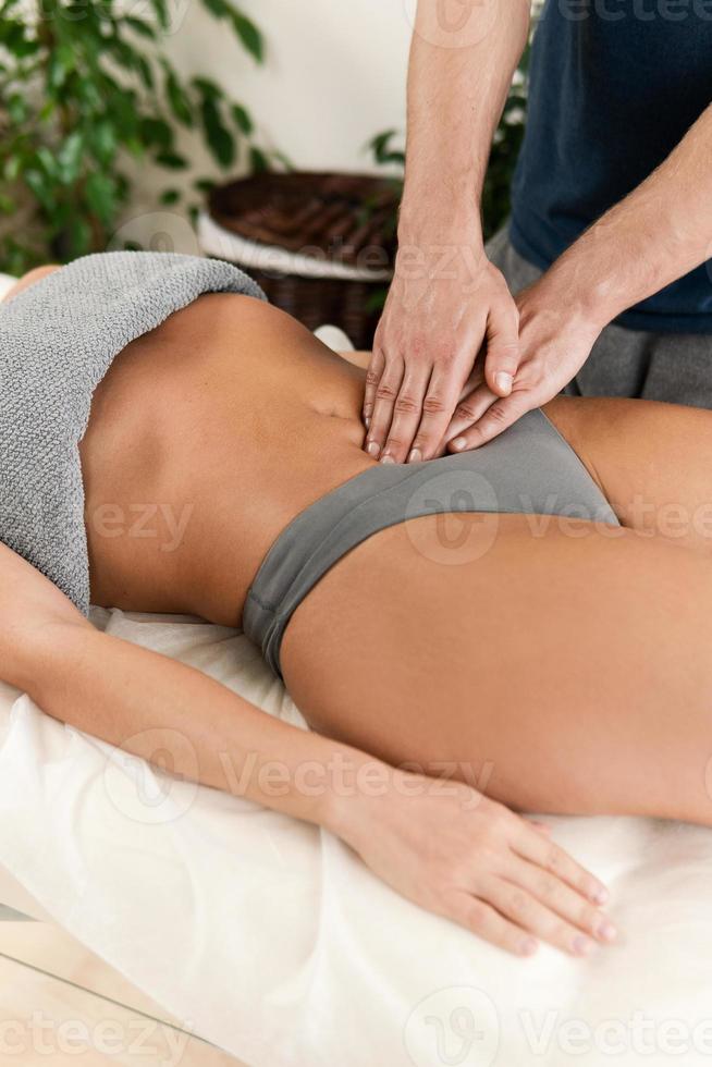 Closeup of masseur man's hands during stomach massage photo