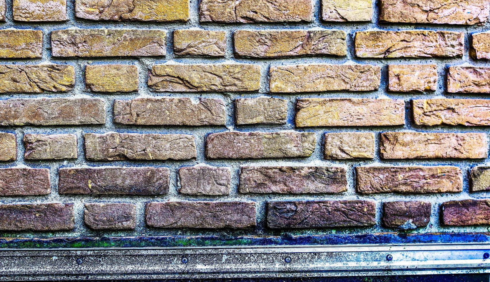 Detailed view at a colorful old and weathered brick wall texture as a panoramic background. photo