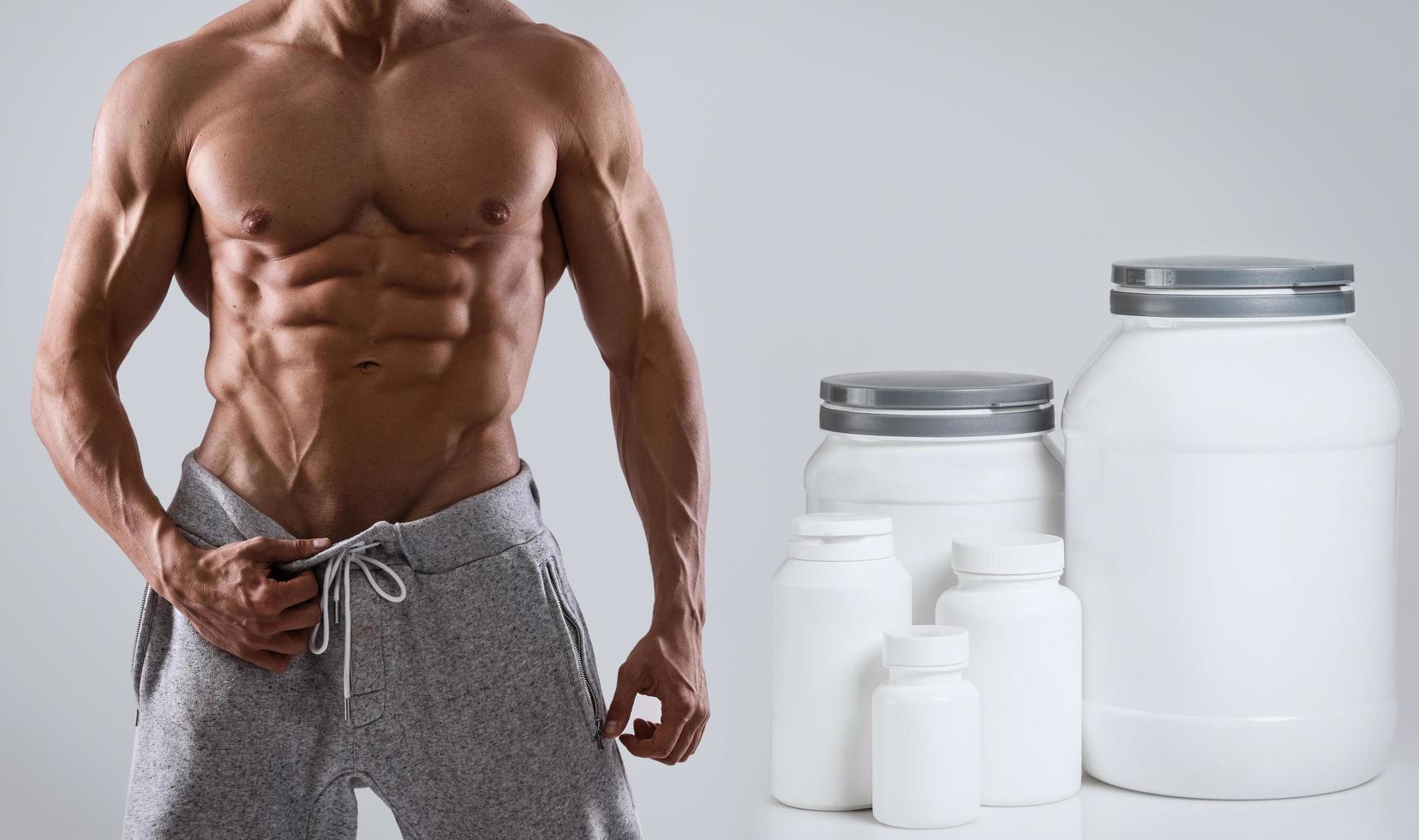 Muscular male torso with different food supplements photo