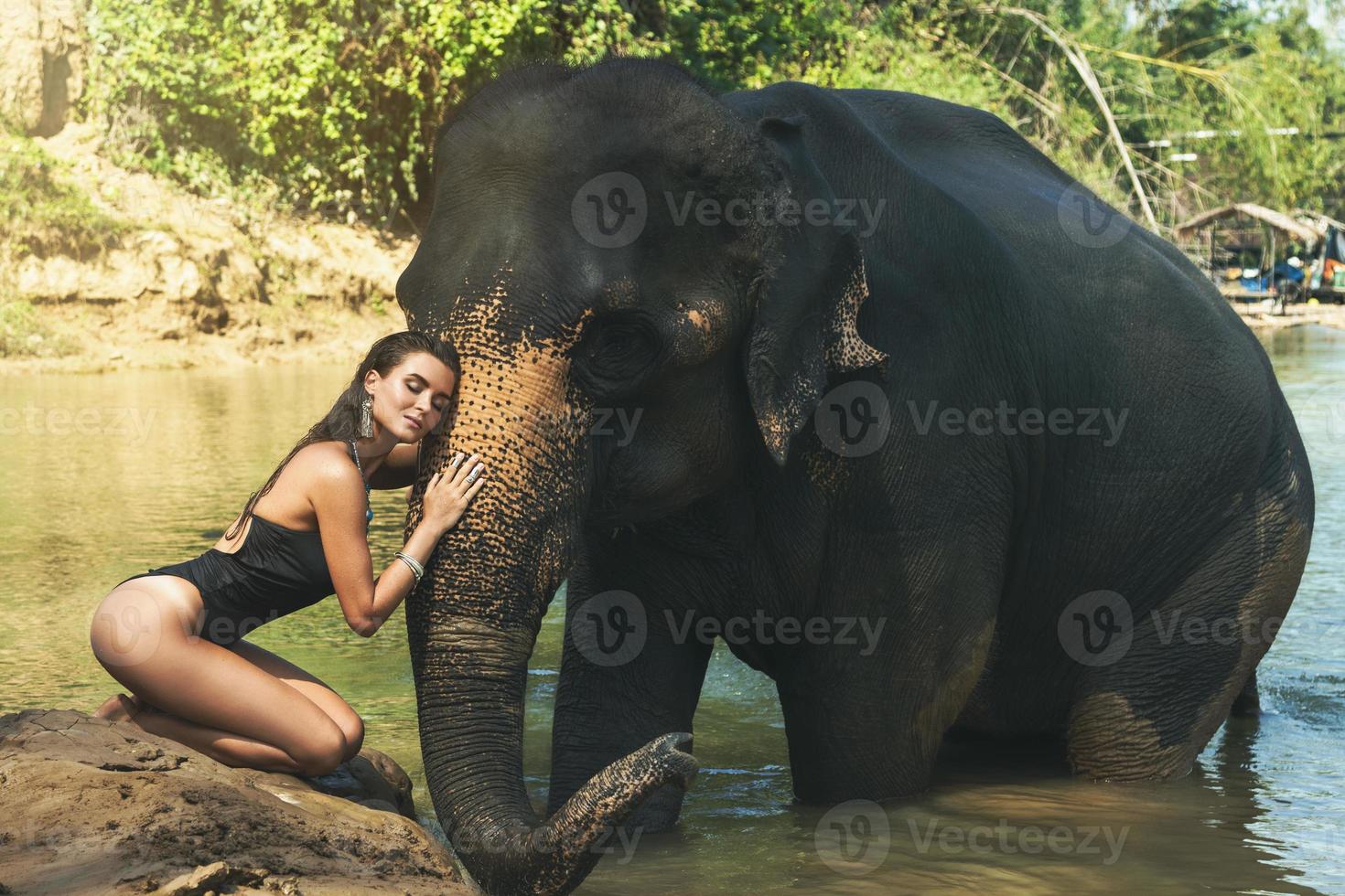 mujer feliz se está bañando con el elefante en el río foto