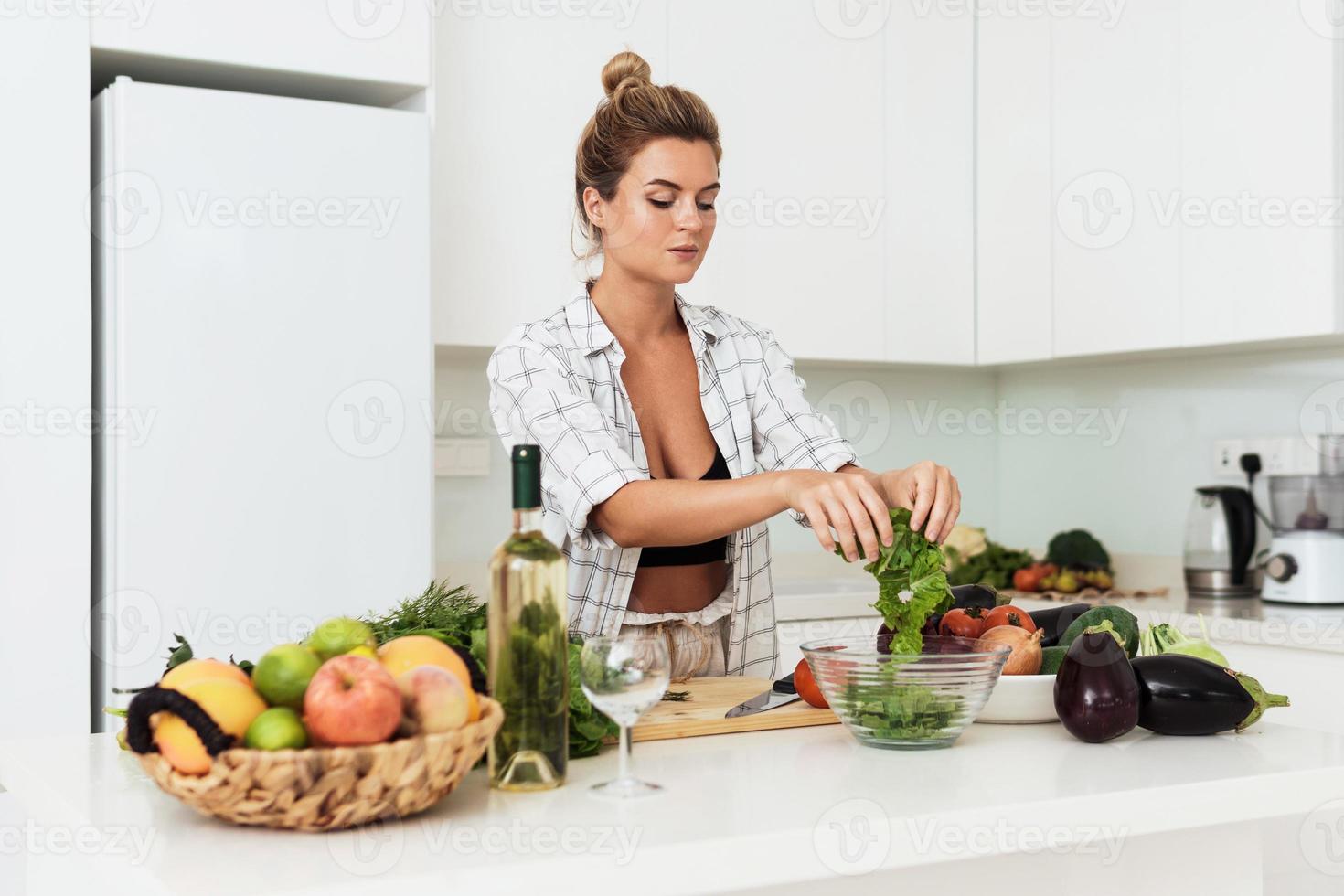 Young pretty woman tearing lettuce into bowl for salad photo