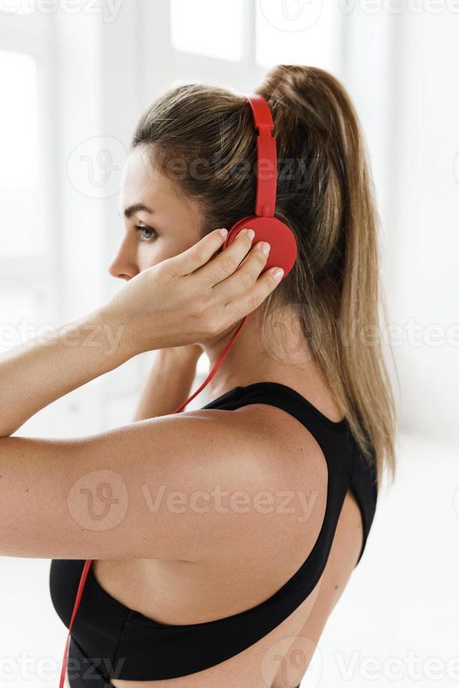 mujer deportiva con auriculares rojos escuchando música para hacer