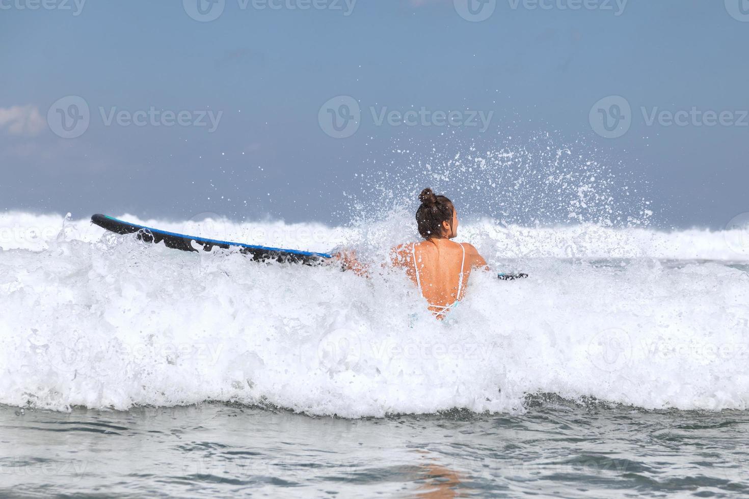 Woman surfer is trying to get into line up trough waves during her surfing workout photo