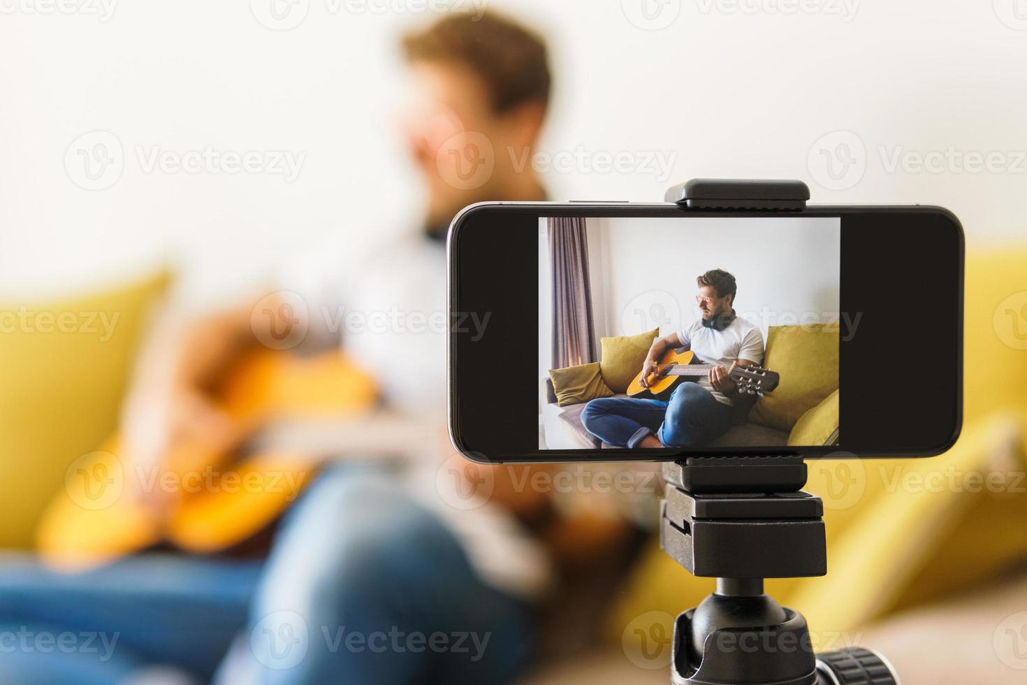 Musician blogger on sofa playing acoustic guitar photo