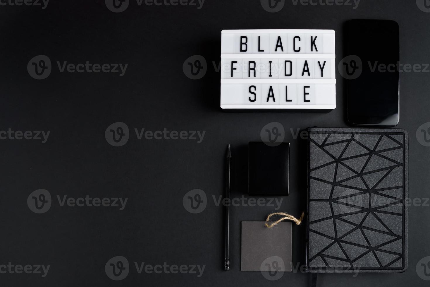 Black Friday online sale concept. Monochromatic flatlay on dark background. Smartphone and accessories. photo