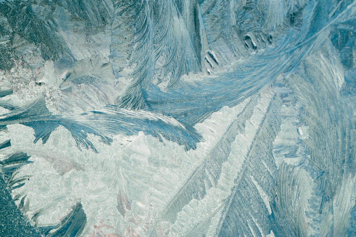 Frosty patterns on glass. Christmas background. Blue ice on winter window. photo
