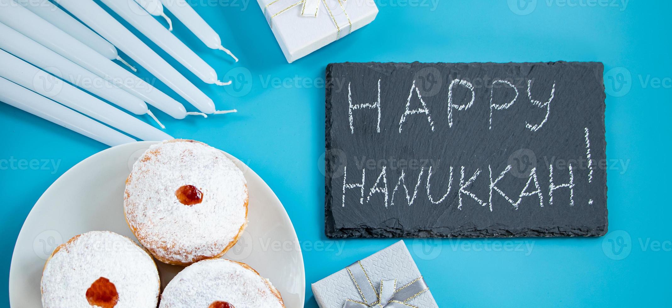 Happy Hanukkah. Jewish dessert sufganiyot donuts on blue background. Symbol of religious Judaism holiday. Inscription on chalk board. photo