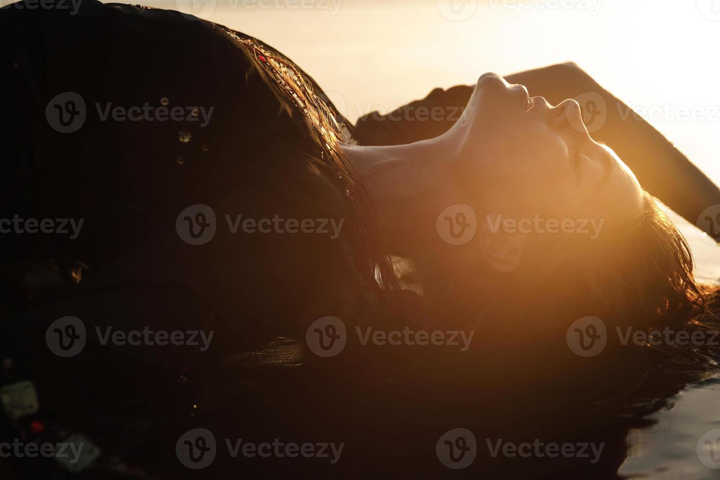 mujer sexy con túnica negra posa en la playa con arena negra foto