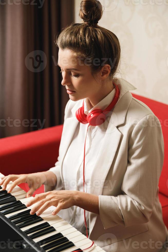 mujer joven músico tocando sintetizador en casa foto