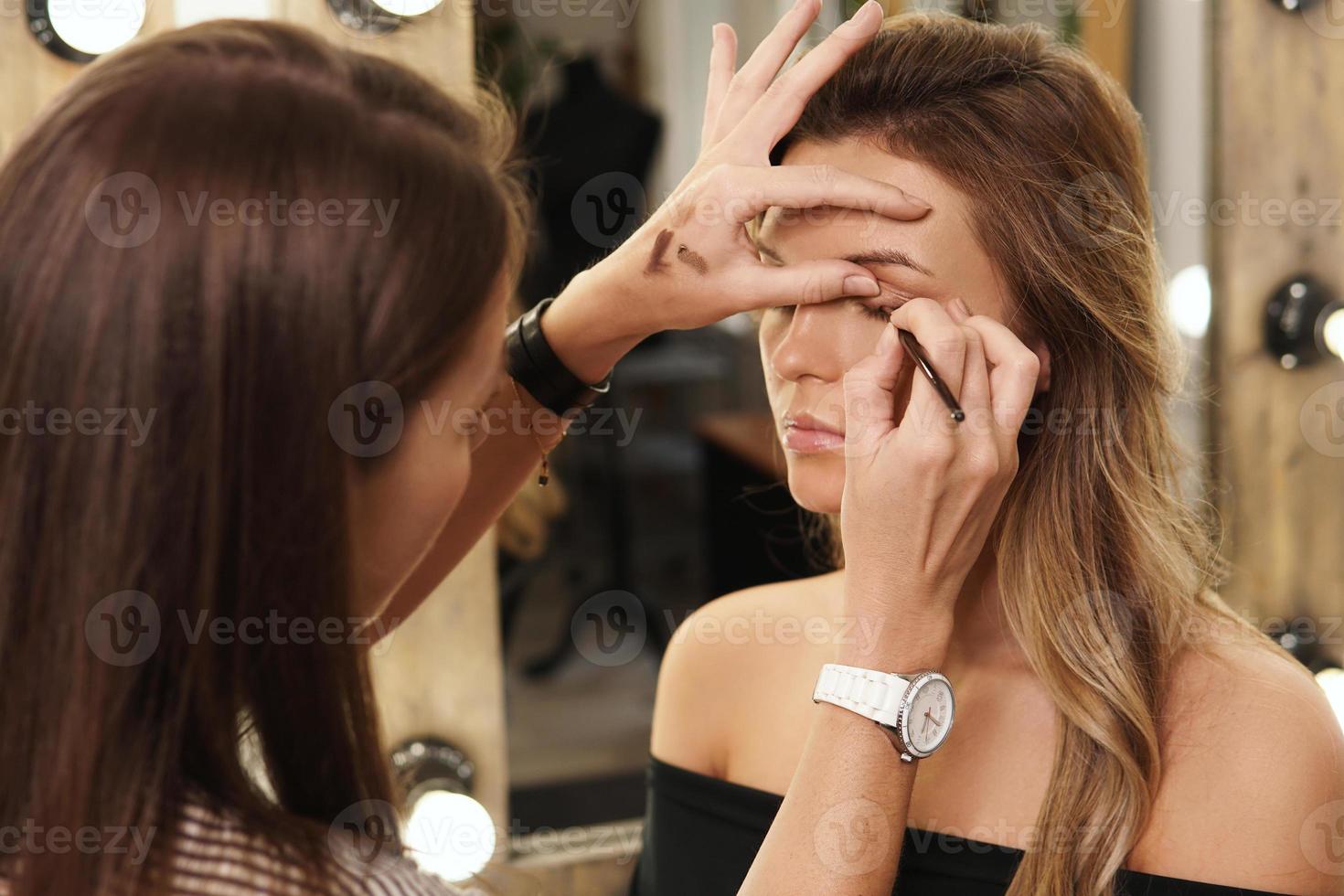 Pofessional make-up artist and her working process during makeup routine for young and beautiful model photo