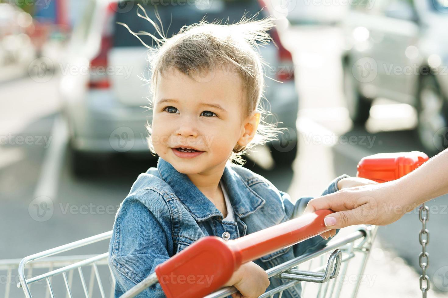 lindo niño sentado en un carrito de compras foto