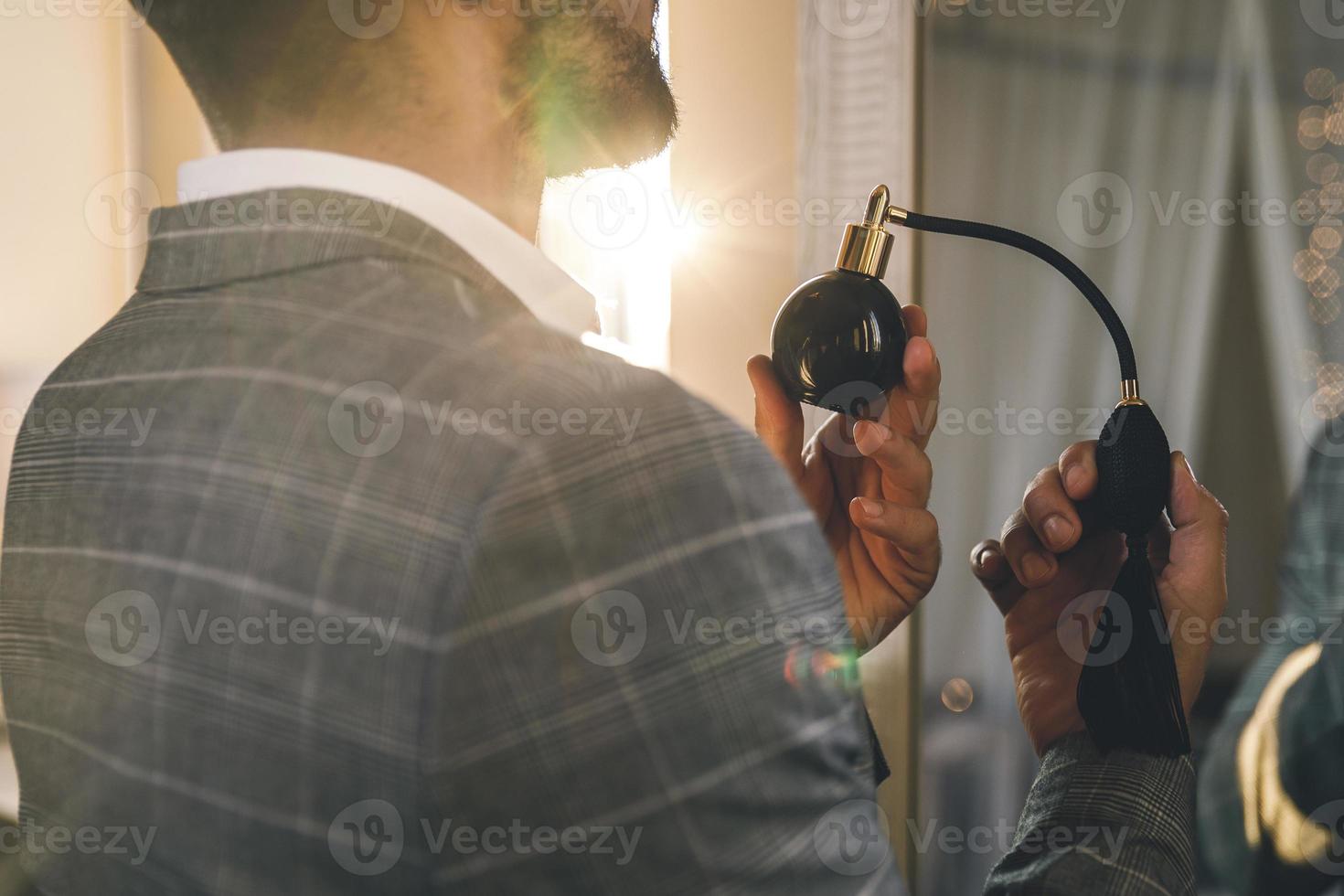 Man is using atomizer nozzle with perfume photo