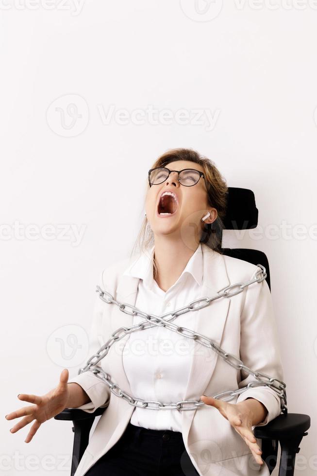 Angry business woman tied up to the office chair with a chains photo