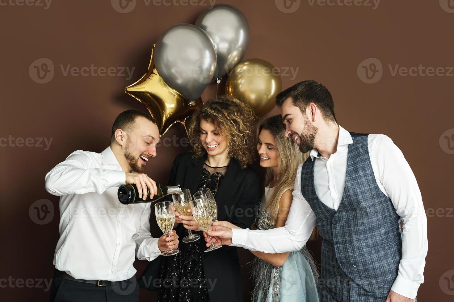 fiesteros bien vestidos celebrando vacaciones o eventos y bebiendo vino espumoso foto