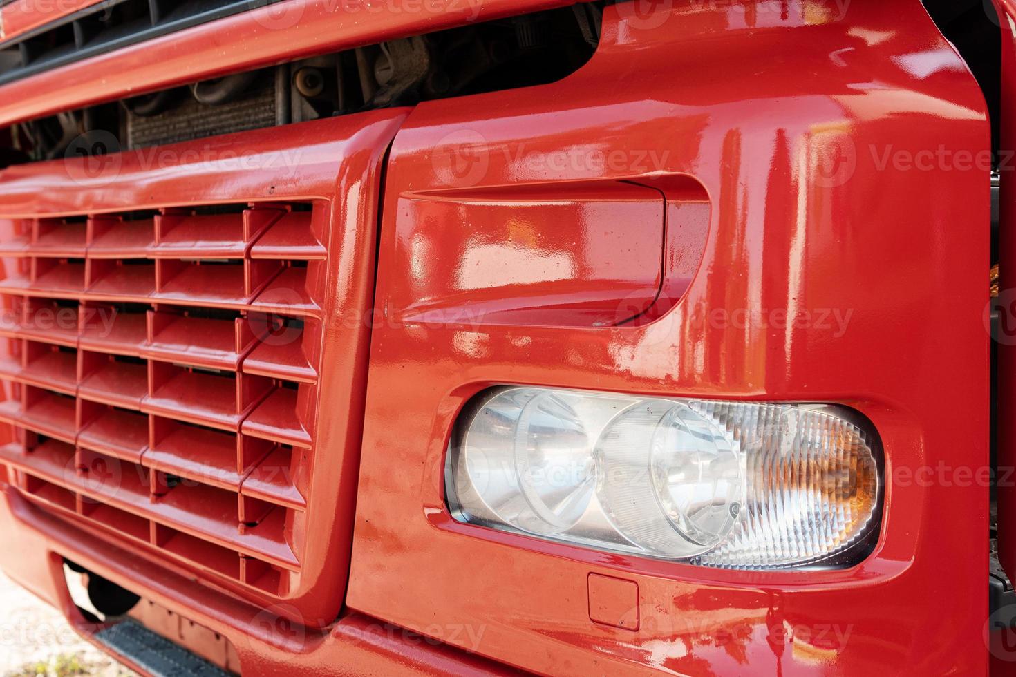 Front part of the red truck with radiator grille and headlight photo