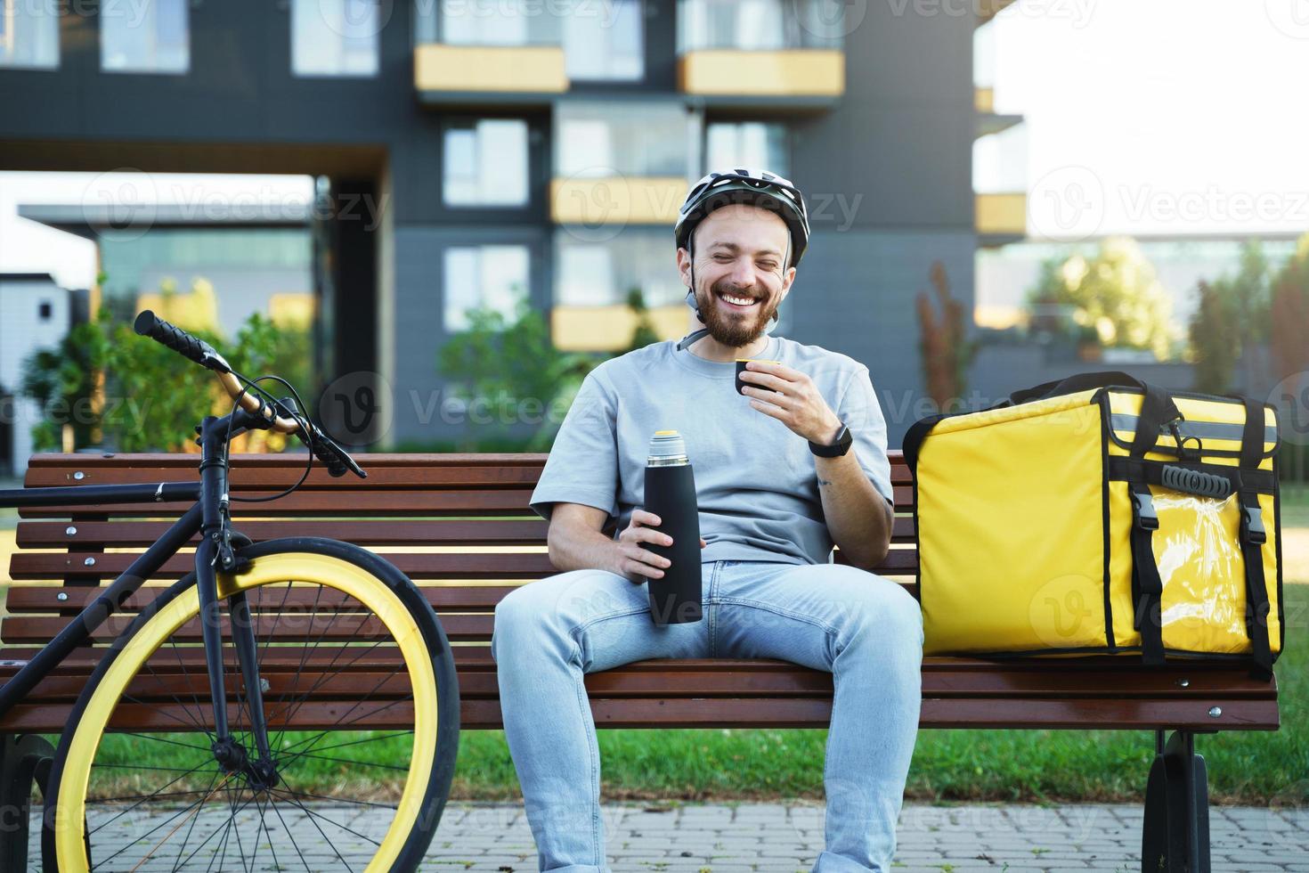 mensajero de entrega urgente sentado en un banco y tomando café. foto