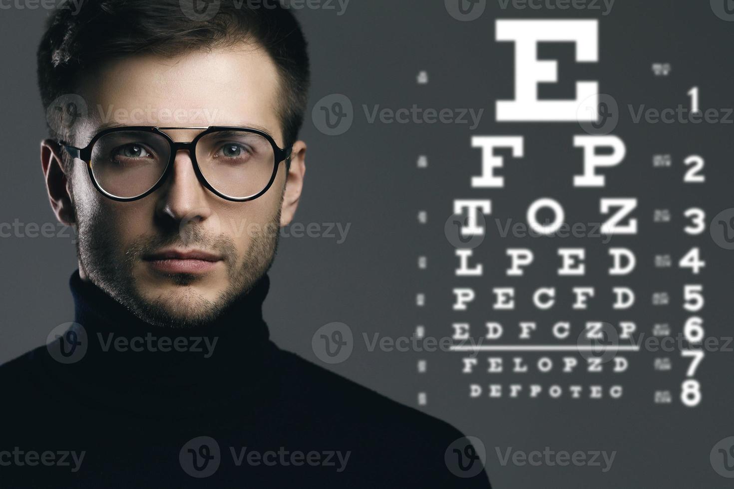 hombre guapo con anteojos y tabla optométrica foto