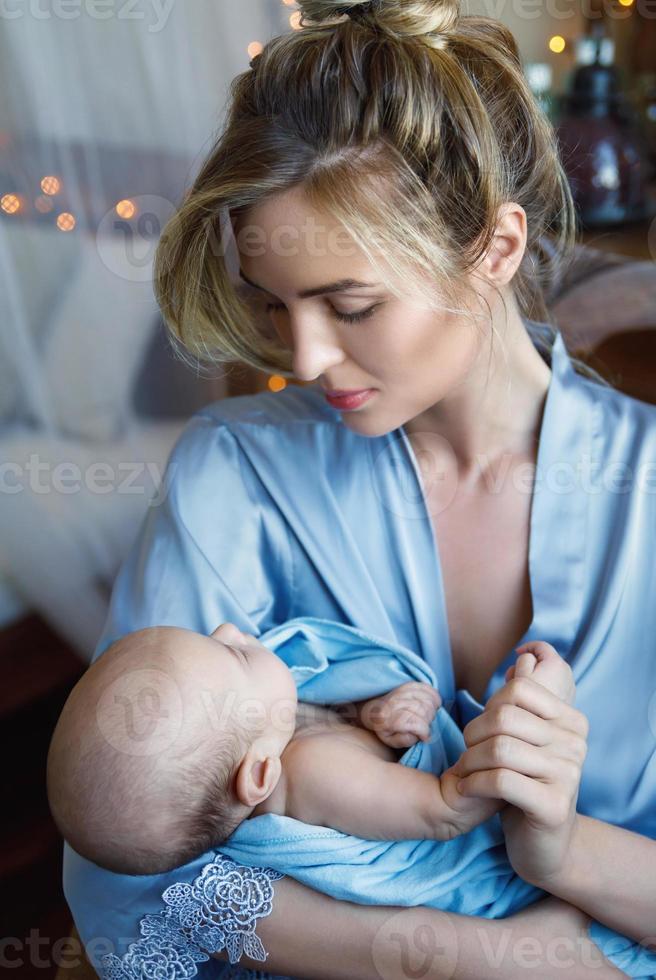 Young beautiful mother with her cute little baby wrapped in the blue cloth photo