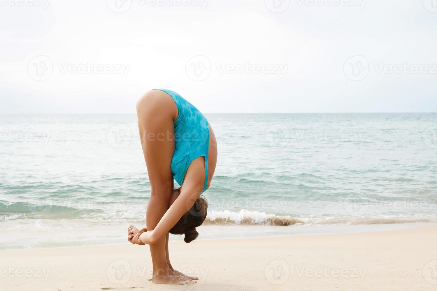 Woman doing yoga exercises on the beach photo