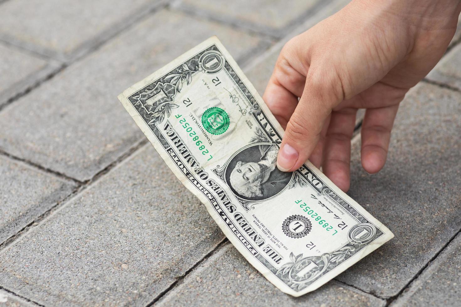 Woman is picking one dollar banknote from the ground. photo