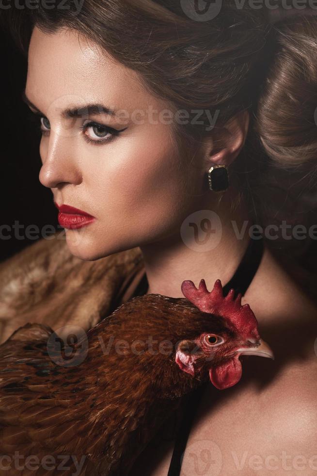 Gorgeous woman with beautiful makeup and hairstyle holding hen photo