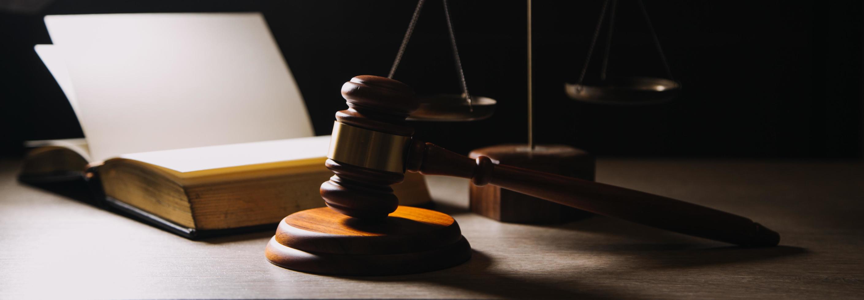 Justice and law concept.Male judge in a courtroom with the gavel, working with, computer and docking keyboard, eyeglasses, on table in morning light photo