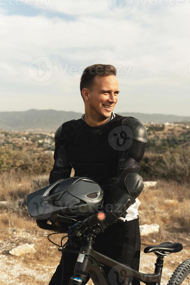 Downhill rider fully equipped with protective gear and his bicycle photo