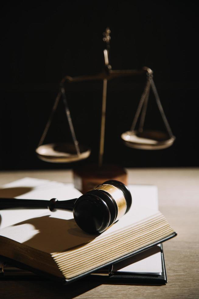 Justice and law concept.Male judge in a courtroom with the gavel, working with, computer and docking keyboard, eyeglasses, on table in morning light photo