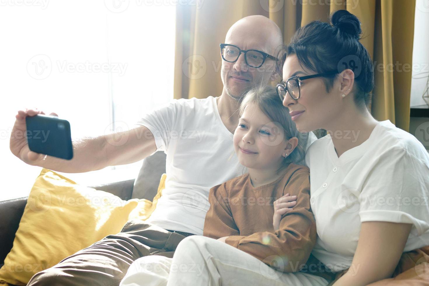 Happy family taking selfie using smartphone at home photo