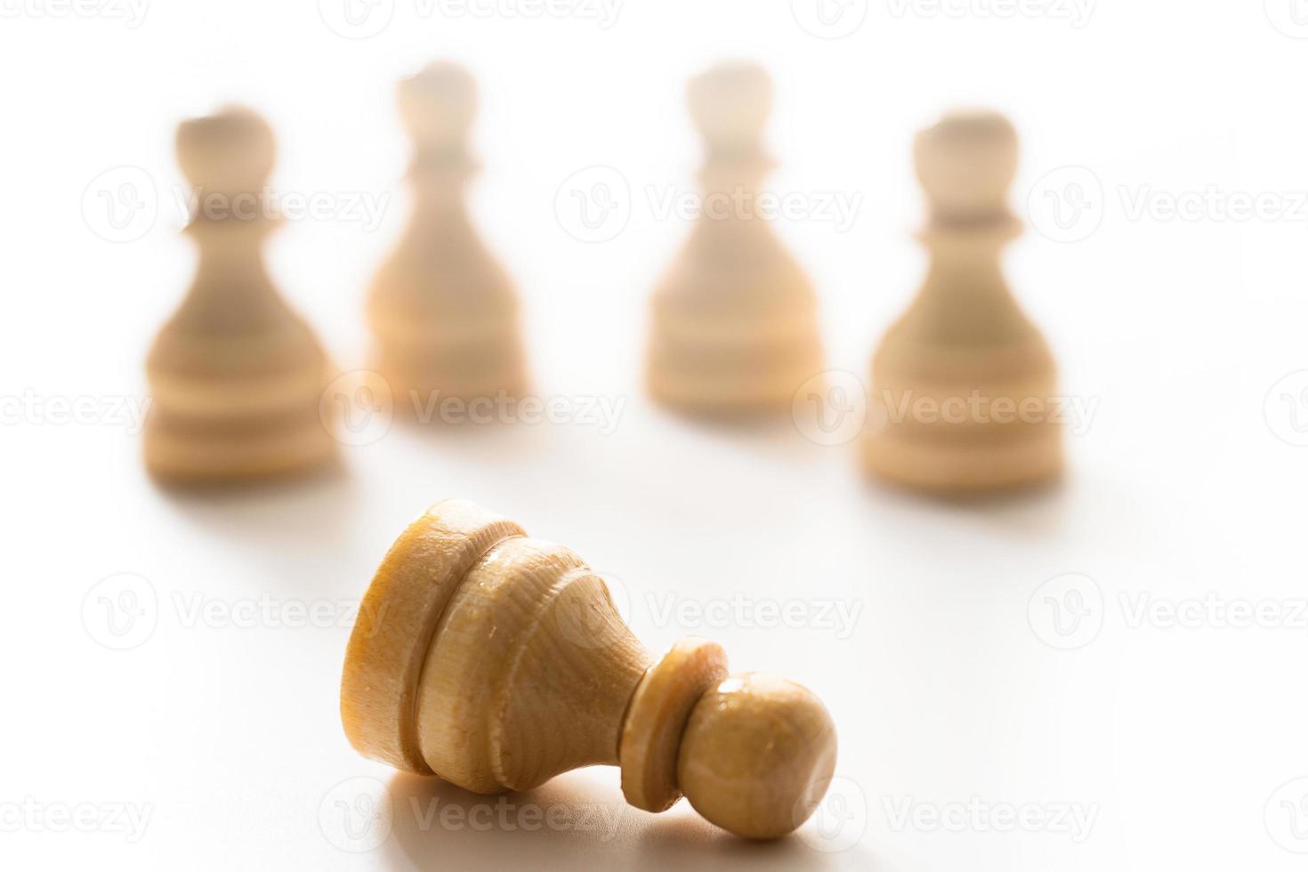 Wooden chessmen standing with one chess pawn lying. photo