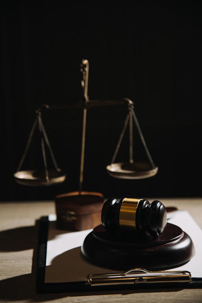 Justice and law concept.Male judge in a courtroom with the gavel, working with, computer and docking keyboard, eyeglasses, on table in morning light photo