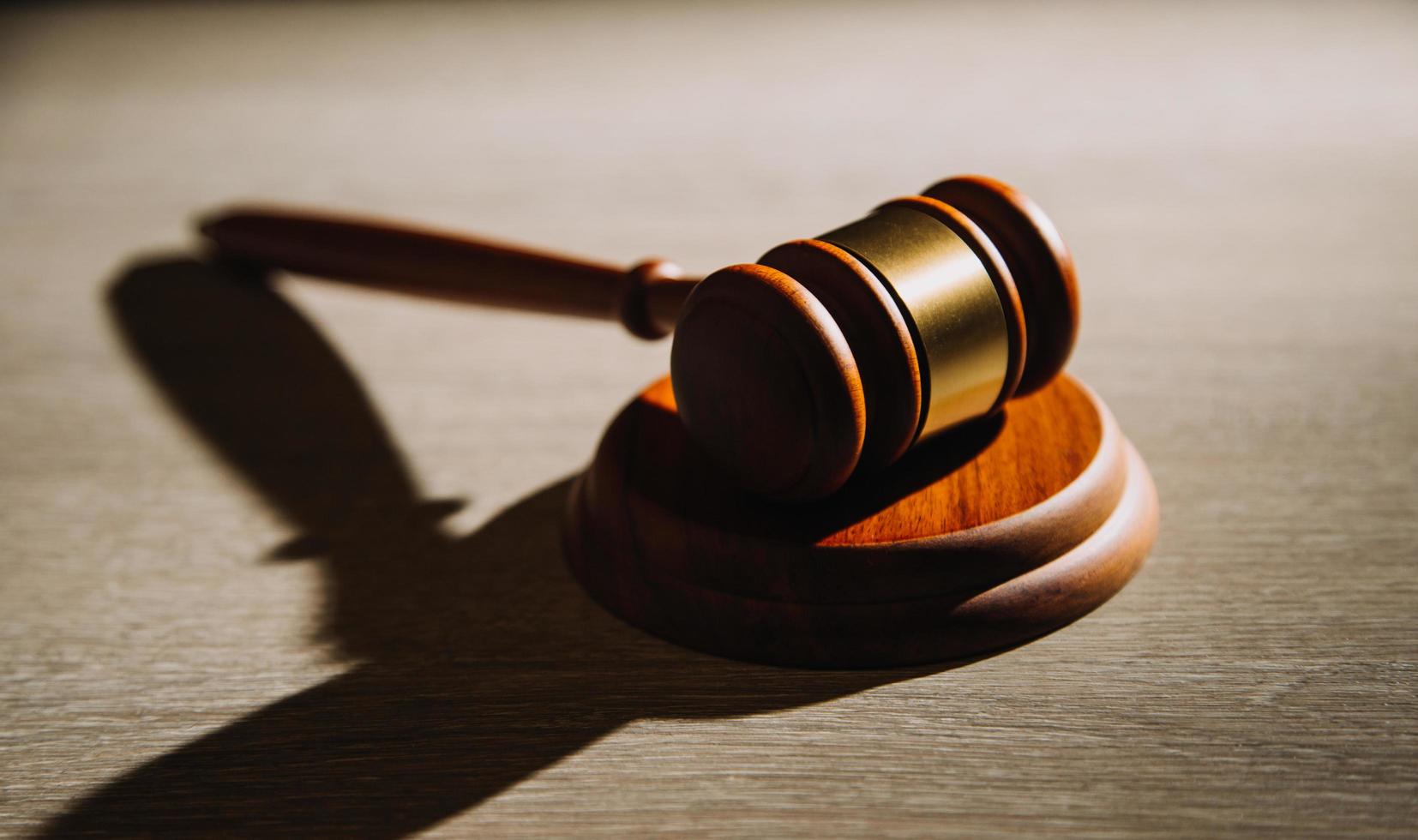 Justice and law concept.Male judge in a courtroom with the gavel, working with, computer and docking keyboard, eyeglasses, on table in morning light photo