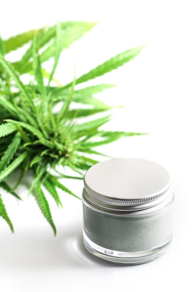 Green cannabis plant and jar with a moisturizing cream photo