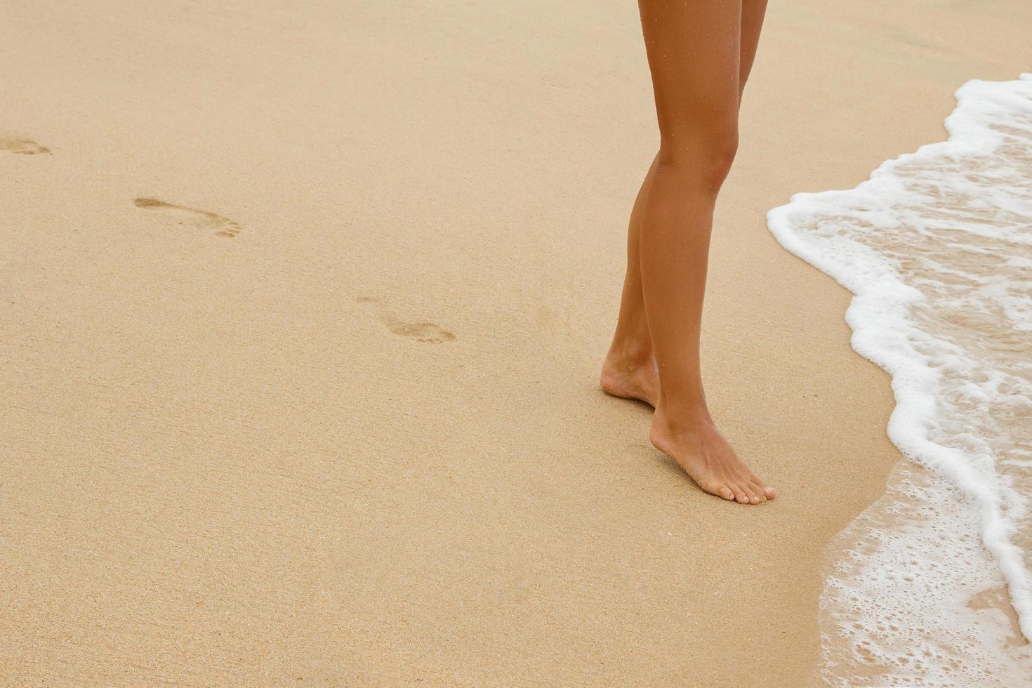 Female legs and foot prints on the sand photo