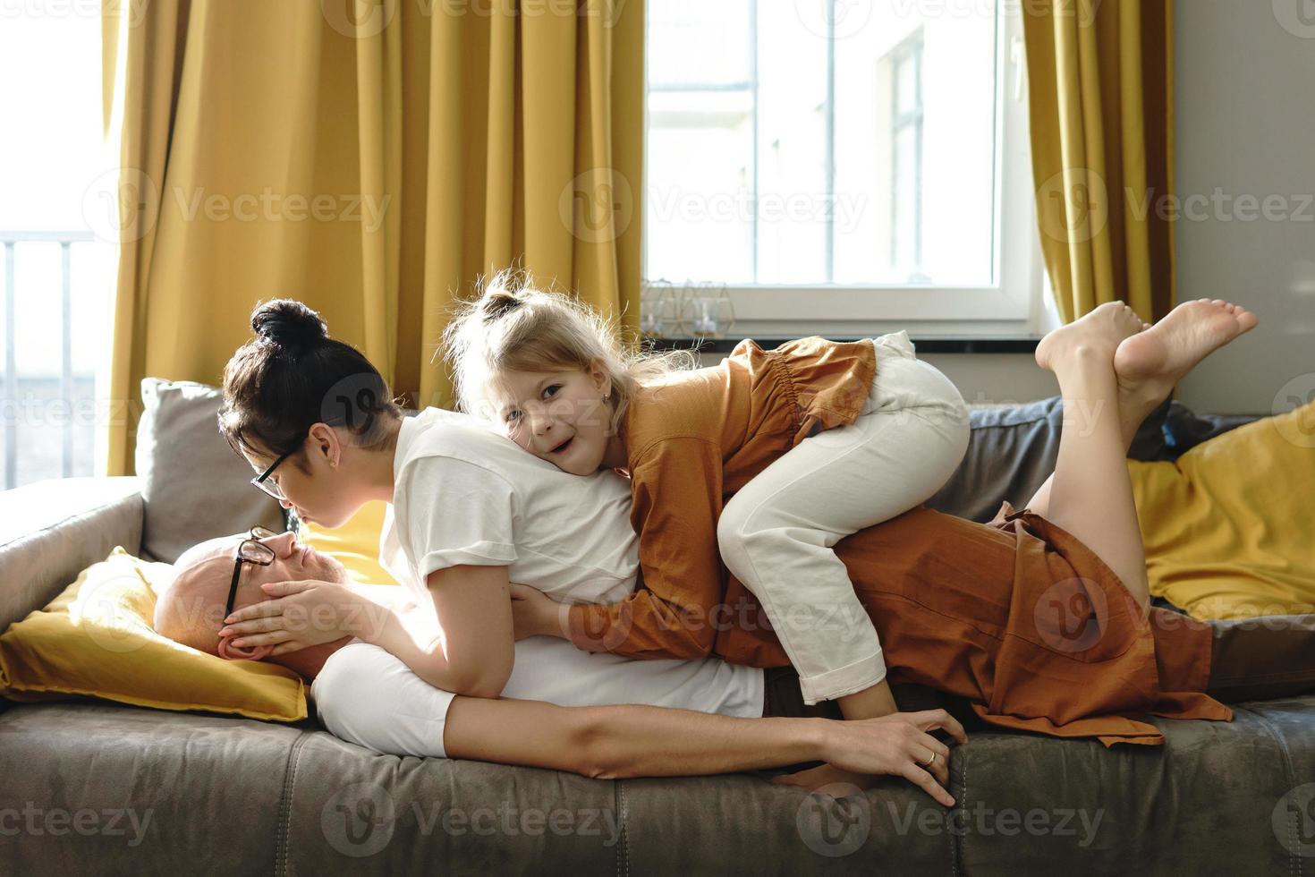 Happy family lying on the sofa and having fun at home photo