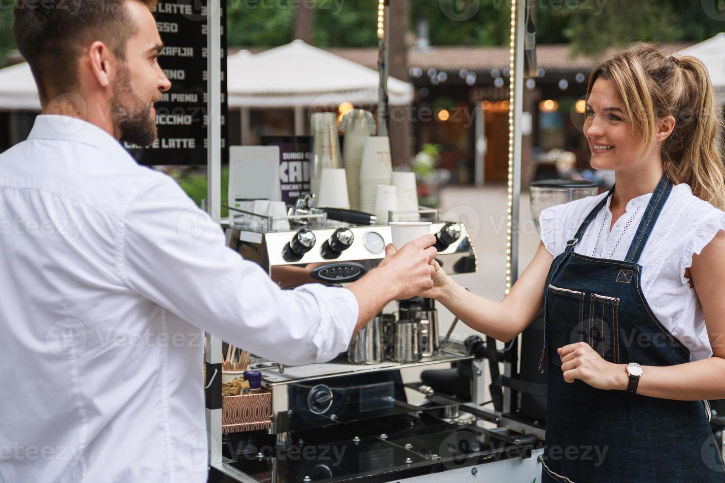 Beautiful woman barista selling coffee to the customer photo