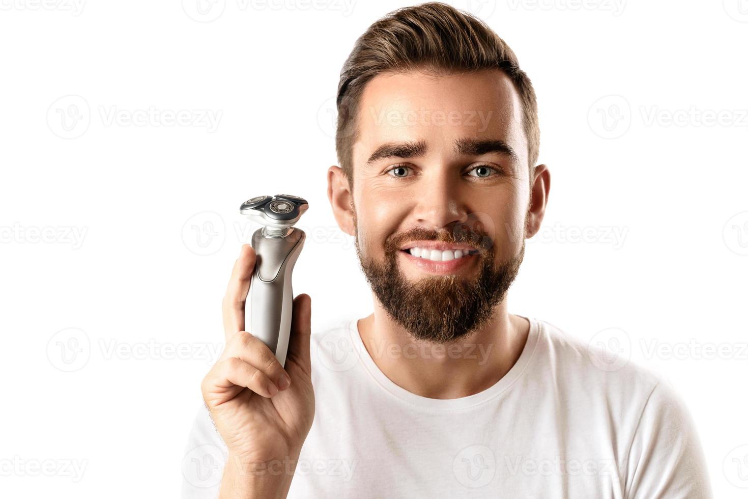 Handsome bearded man holding electric shaver in his hand photo