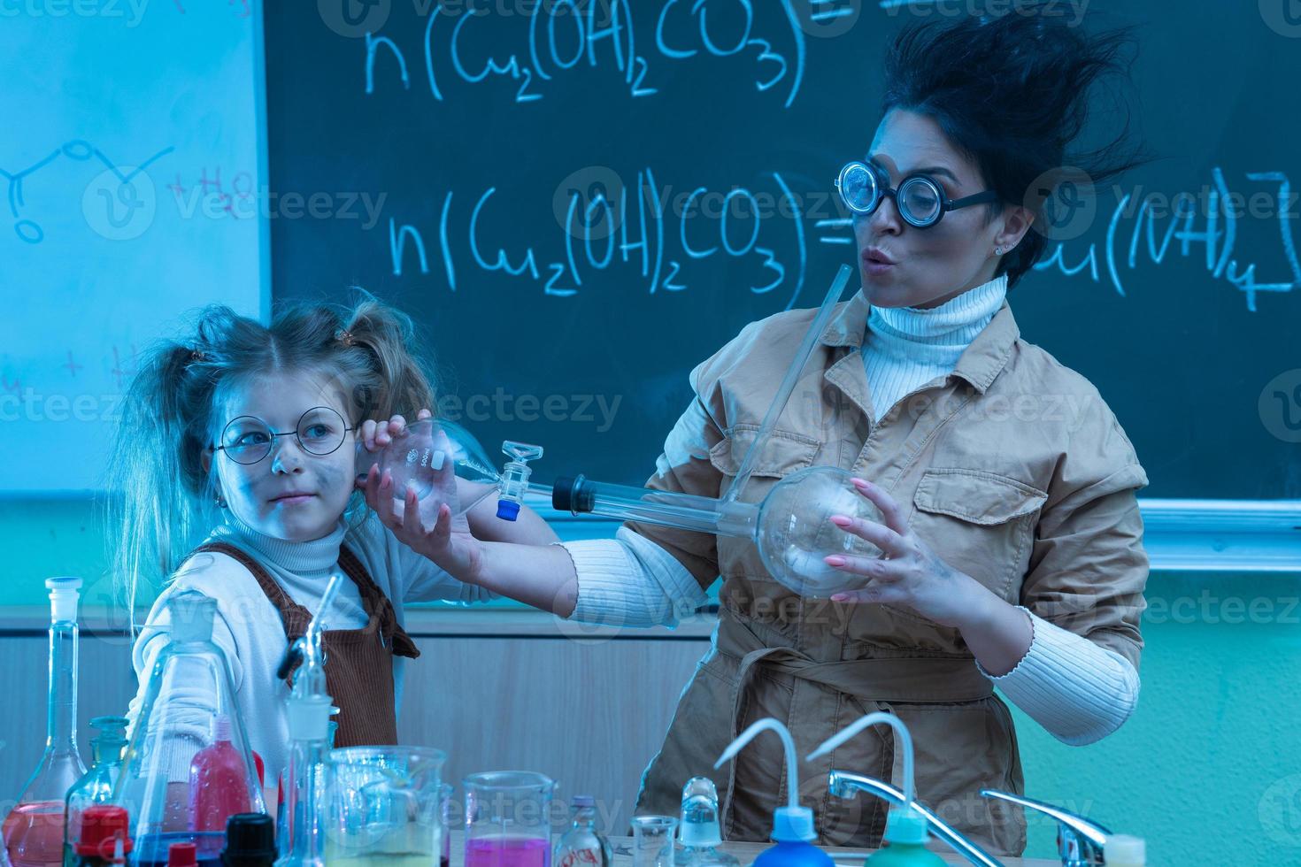 Teacher and little girl during chemistry lesson mixing chemicals in a laboratory photo