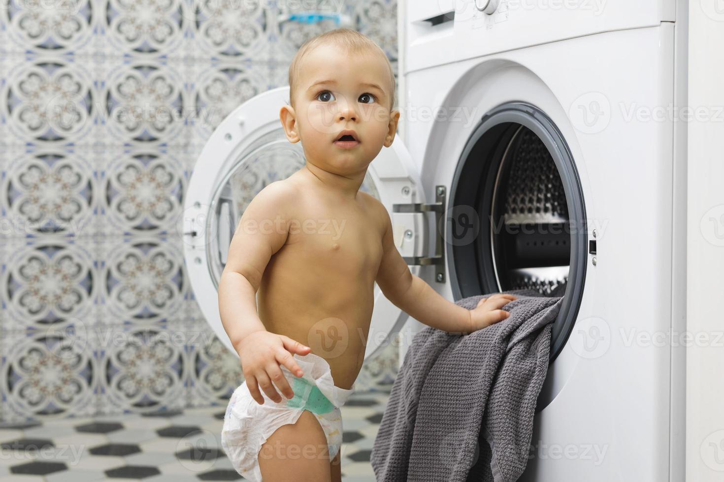 Cute baby boy beside the washing machine photo